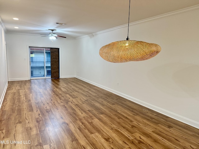 spare room featuring a ceiling fan, crown molding, wood finished floors, and baseboards