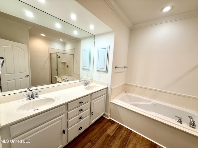 bathroom featuring wood finished floors, double vanity, a stall shower, ornamental molding, and a sink