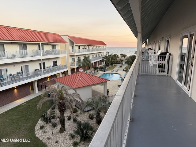 balcony at dusk featuring a water view