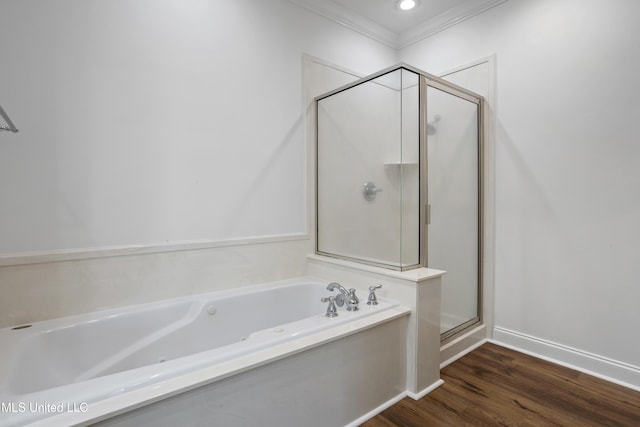 bathroom featuring wood finished floors, baseboards, a stall shower, ornamental molding, and a garden tub