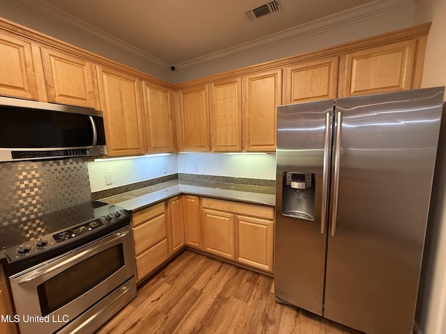 kitchen featuring visible vents, ornamental molding, stainless steel appliances, light wood-style floors, and backsplash