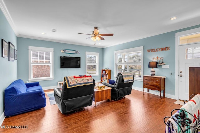 living area with ornamental molding, visible vents, baseboards, and wood finished floors