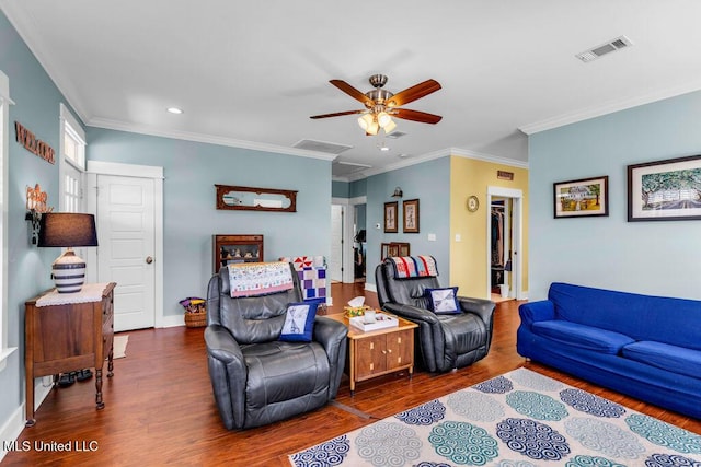 living area featuring wood finished floors, visible vents, baseboards, attic access, and crown molding