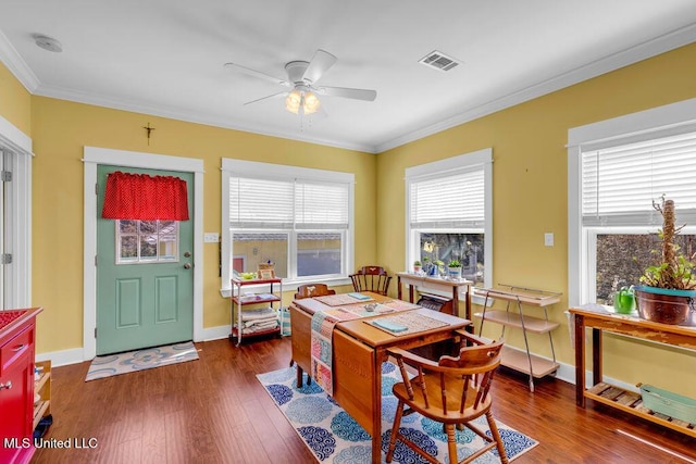 dining room with visible vents, baseboards, ceiling fan, wood finished floors, and crown molding