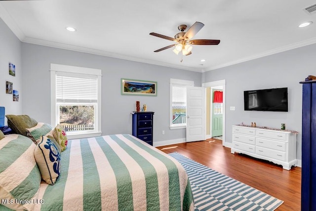 bedroom featuring ornamental molding, multiple windows, baseboards, and wood finished floors