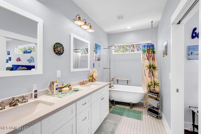 bathroom featuring a freestanding tub, visible vents, a sink, and double vanity