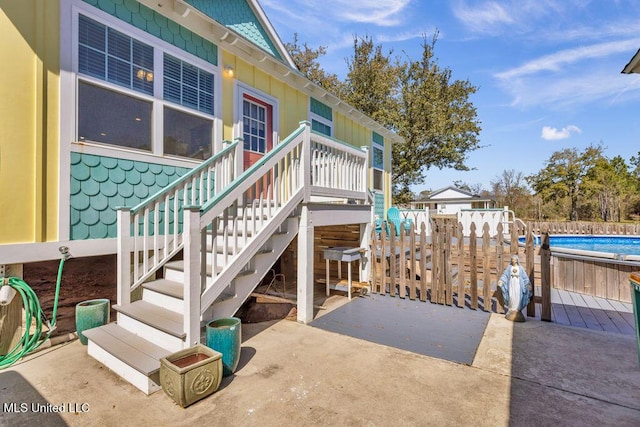 exterior space with stairs, a patio area, a wooden deck, and an outdoor pool