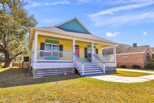 view of front of property with a shingled roof, a porch, and a front yard