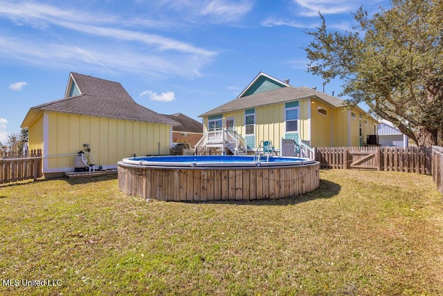 back of property featuring a fenced in pool, a fenced backyard, and a yard