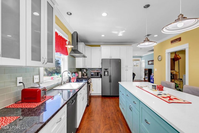 kitchen with glass insert cabinets, stainless steel appliances, wall chimney range hood, white cabinetry, and a sink