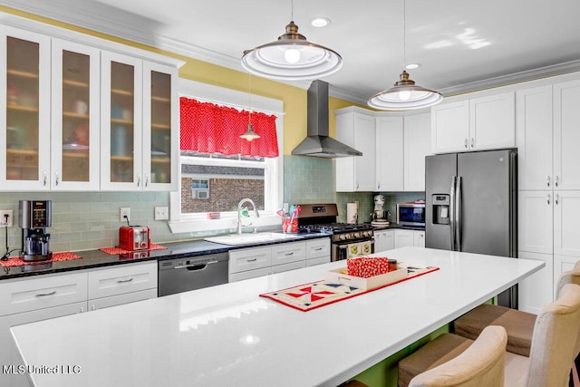 kitchen featuring a breakfast bar area, stainless steel appliances, a sink, wall chimney range hood, and crown molding