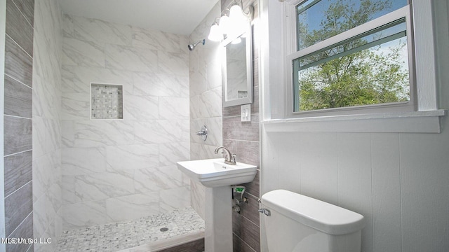 full bathroom featuring a tile shower and toilet