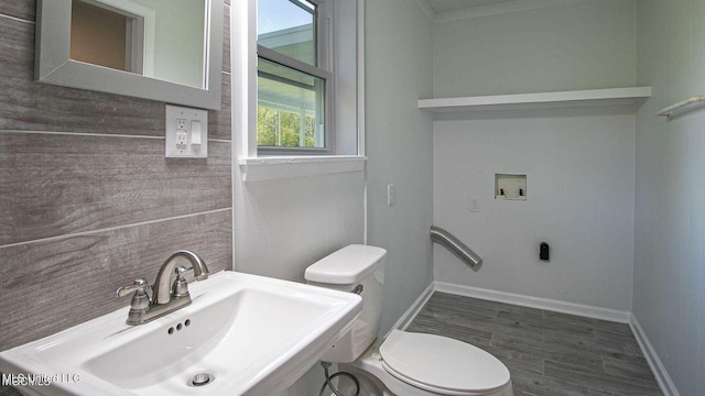 bathroom with baseboards, a sink, toilet, and wood finished floors