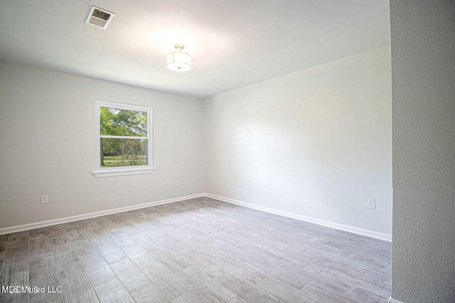 unfurnished room featuring wood finished floors, visible vents, and baseboards