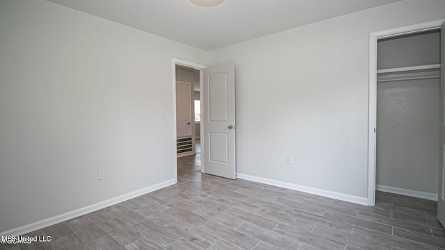 unfurnished bedroom featuring wood finish floors, a closet, and baseboards