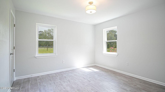 unfurnished room featuring a wealth of natural light, baseboards, and wood finished floors