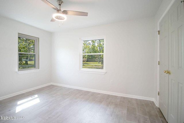 empty room featuring light wood finished floors, baseboards, and a wealth of natural light