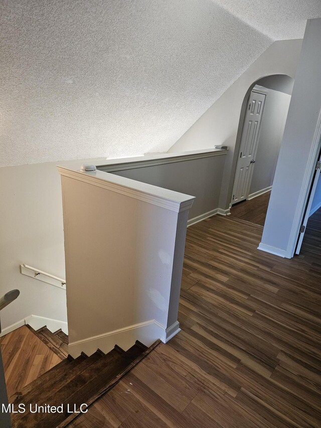 5746 Eagleston Dr, Olive Branch, MS 38654 - staircase featuring baseboards, a textured ceiling, lofted ceiling, arched walkways, and wood finished floors