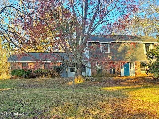 view of front facade with brick siding and a front yard