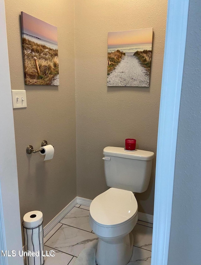 bathroom featuring marble finish floor, toilet, and baseboards