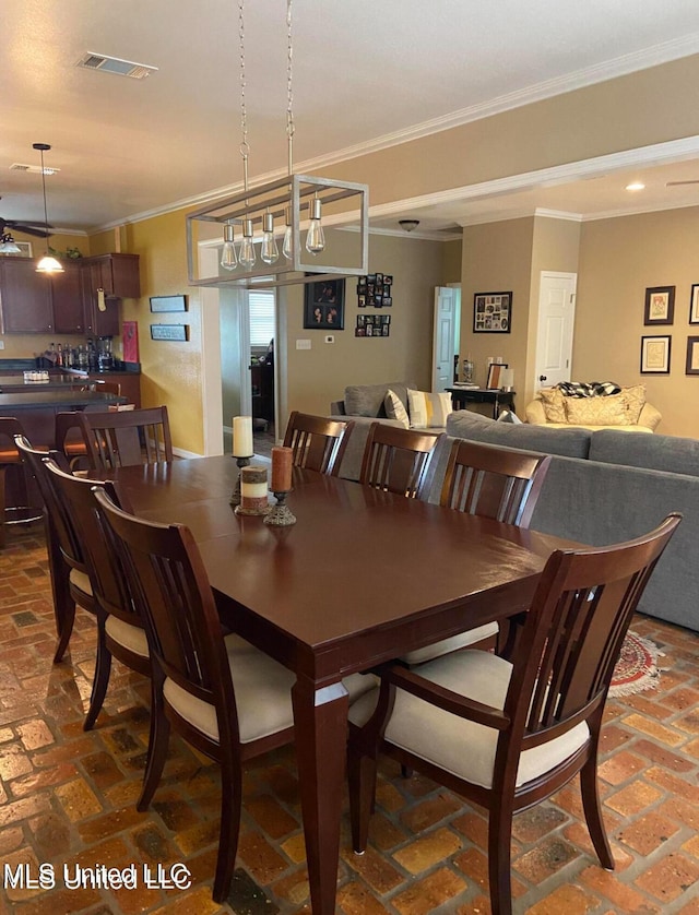 dining space featuring crown molding, brick floor, bar, and visible vents