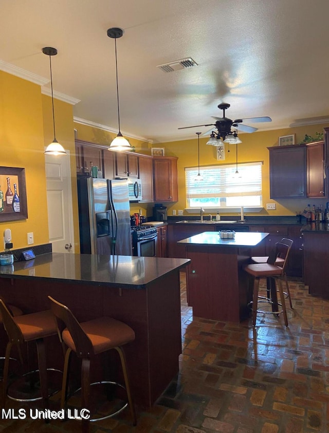 kitchen featuring visible vents, a peninsula, dark countertops, a ceiling fan, and appliances with stainless steel finishes