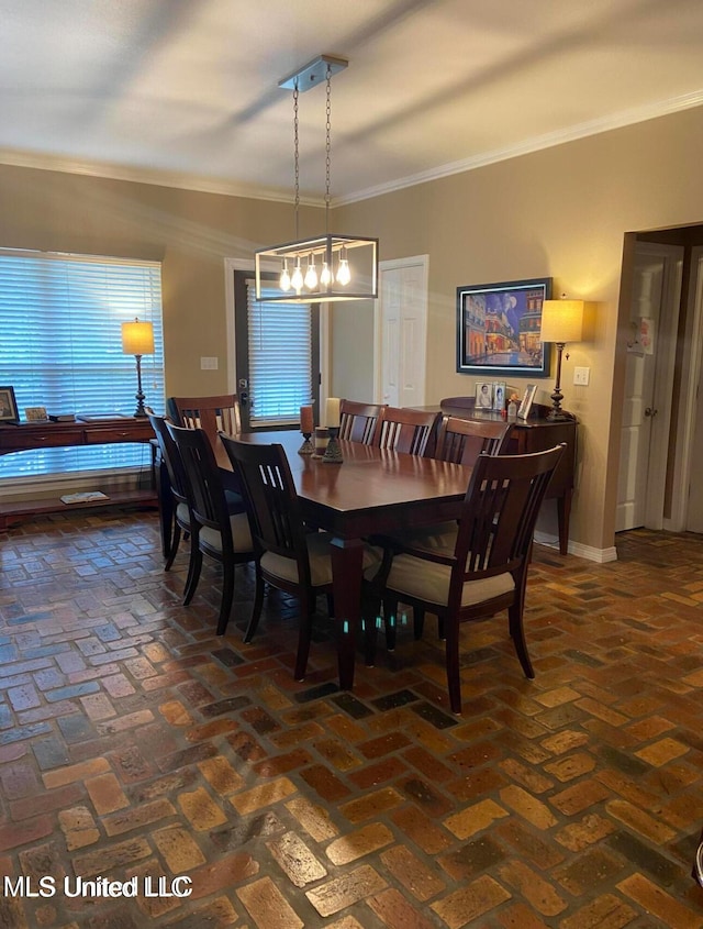 dining room with ornamental molding, brick floor, and baseboards