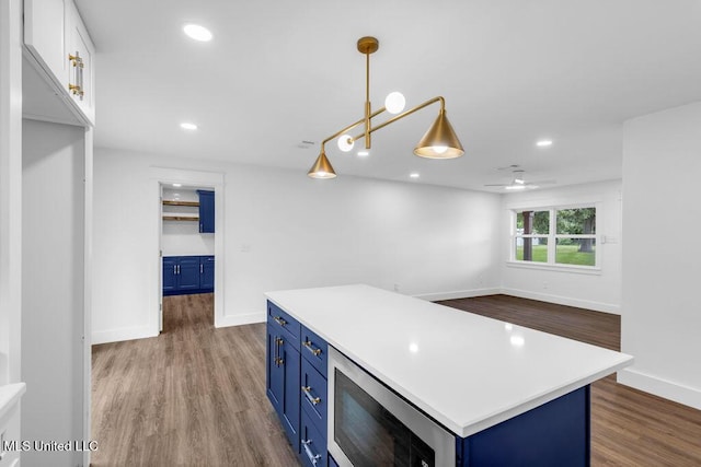 6544 Columbus Cir, Ocean Springs, MS 39564 - kitchen featuring blue cabinetry, stainless steel microwave, wood finished floors, light countertops, and recessed lighting