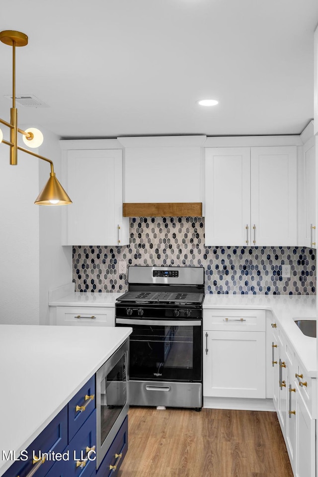 6544 Columbus Cir, Ocean Springs, MS 39564 - kitchen featuring appliances with stainless steel finishes, blue cabinetry, white cabinetry, light countertops, and decorative backsplash