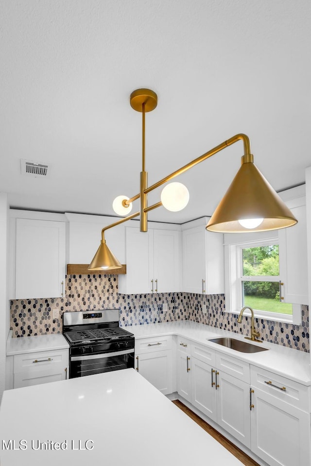 6544 Columbus Cir, Ocean Springs, MS 39564 - kitchen featuring gas range, white cabinetry, tasteful backsplash, and light countertops