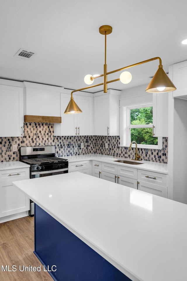 6544 Columbus Cir, Ocean Springs, MS 39564 - kitchen featuring light countertops, backsplash, white cabinetry, light wood finished floors, and stainless steel range with gas cooktop