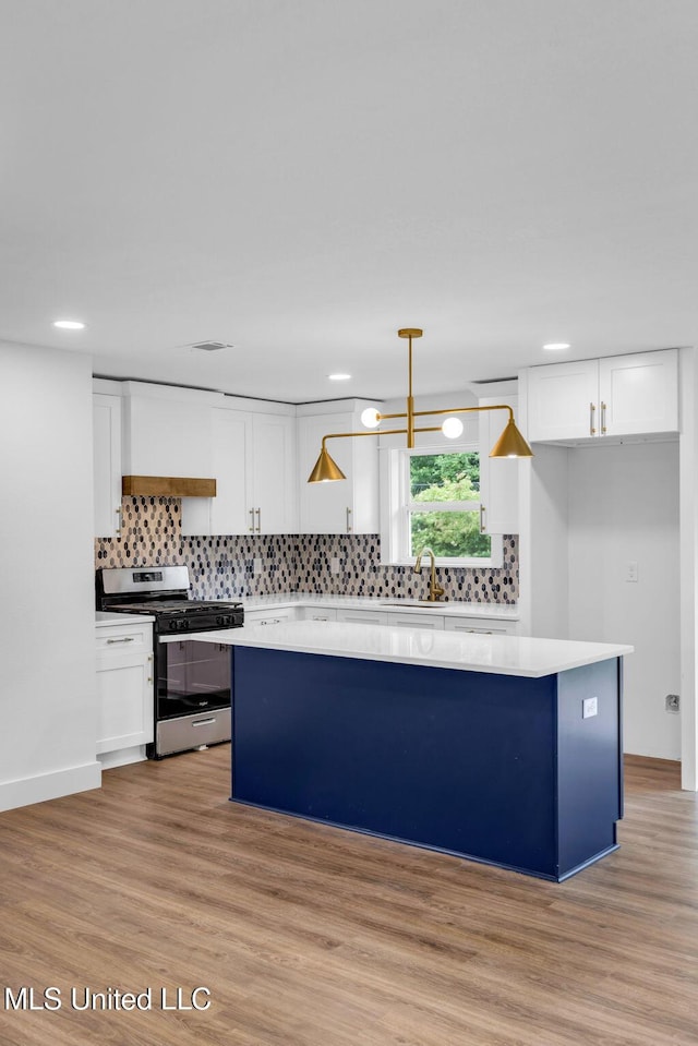 6544 Columbus Cir, Ocean Springs, MS 39564 - kitchen with stainless steel gas range, a center island, white cabinets, decorative backsplash, and recessed lighting