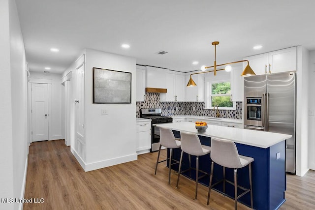 6544 Columbus Cir, Ocean Springs, MS 39564 - kitchen with appliances with stainless steel finishes, white cabinets, light wood-type flooring, and recessed lighting