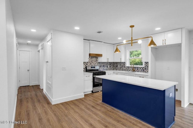 6544 Columbus Cir, Ocean Springs, MS 39564 - kitchen with stainless steel gas stove, white cabinetry, light wood-style floors, decorative backsplash, and recessed lighting