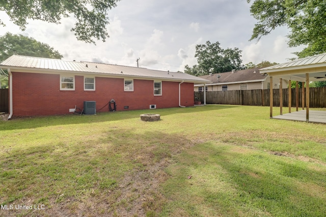 back of property featuring central air condition unit, a yard, fence, and a fire pit