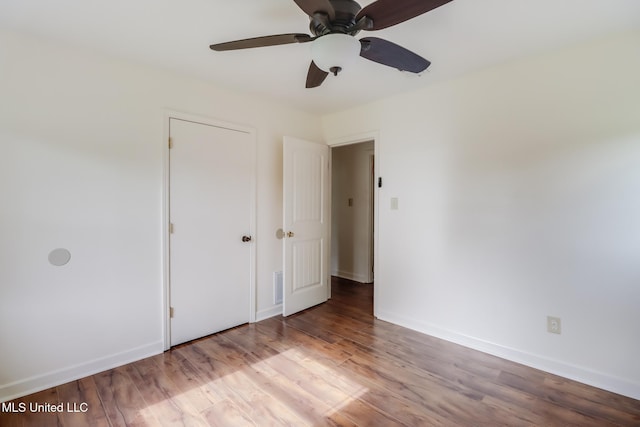 unfurnished bedroom featuring a ceiling fan, visible vents, wood finished floors, and baseboards