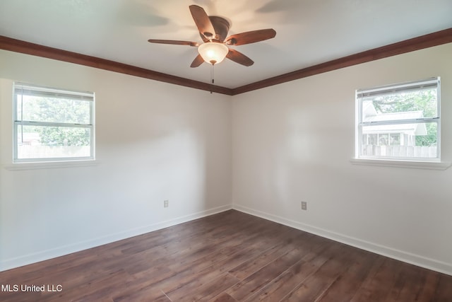 empty room featuring crown molding, baseboards, a healthy amount of sunlight, and dark wood-style floors