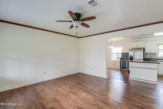 unfurnished living room featuring ceiling fan, crown molding, dark wood-style floors, and visible vents