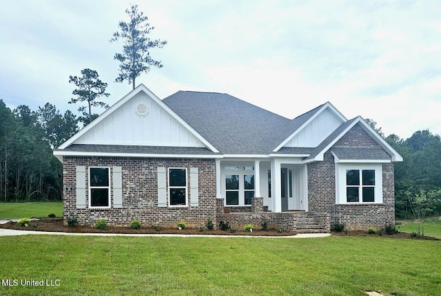 craftsman inspired home featuring roof with shingles, a front lawn, board and batten siding, and brick siding