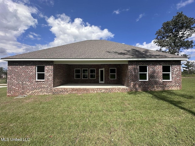 rear view of house featuring a patio, brick siding, a lawn, and a shingled roof