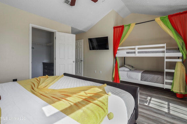 bedroom with lofted ceiling, a closet, a walk in closet, hardwood / wood-style floors, and ceiling fan