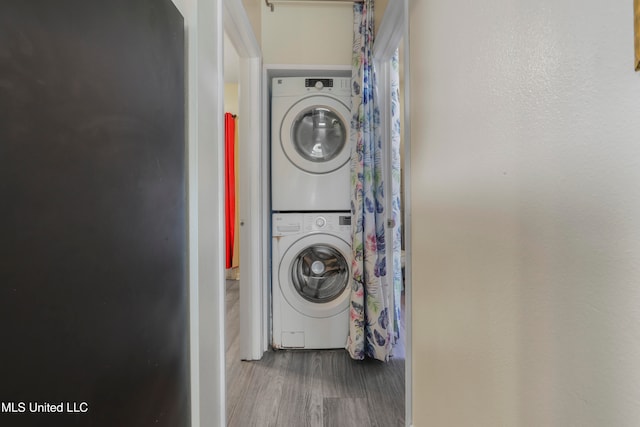 washroom featuring wood-type flooring and stacked washing maching and dryer