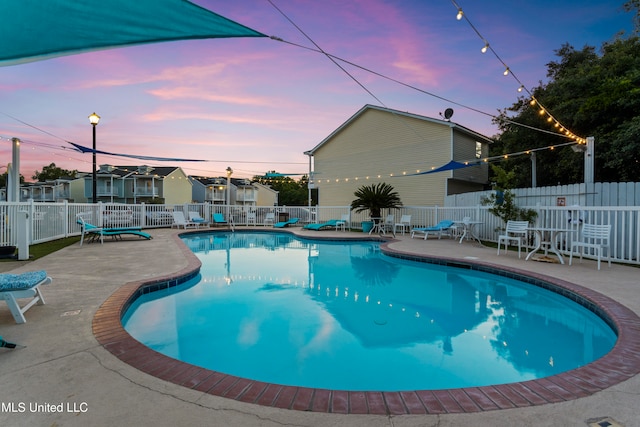 pool at dusk with a patio area