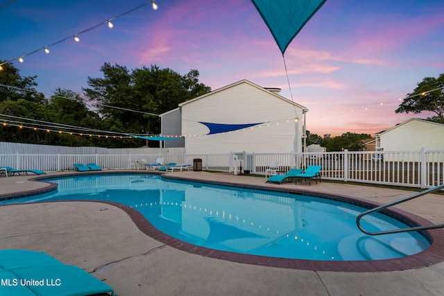 pool at dusk featuring a patio