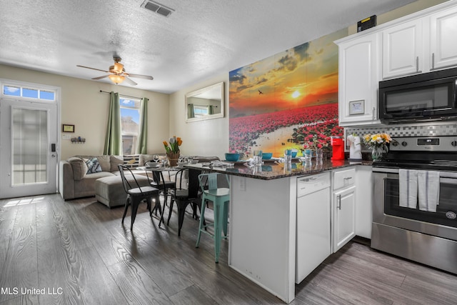 kitchen featuring tasteful backsplash, white dishwasher, electric range, hardwood / wood-style floors, and white cabinets