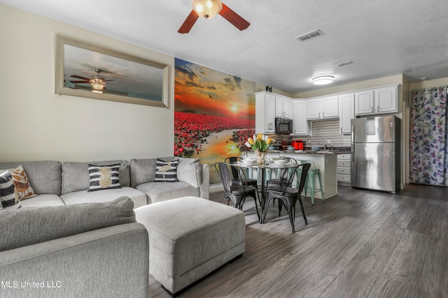 living room featuring sink, dark hardwood / wood-style floors, a textured ceiling, and ceiling fan