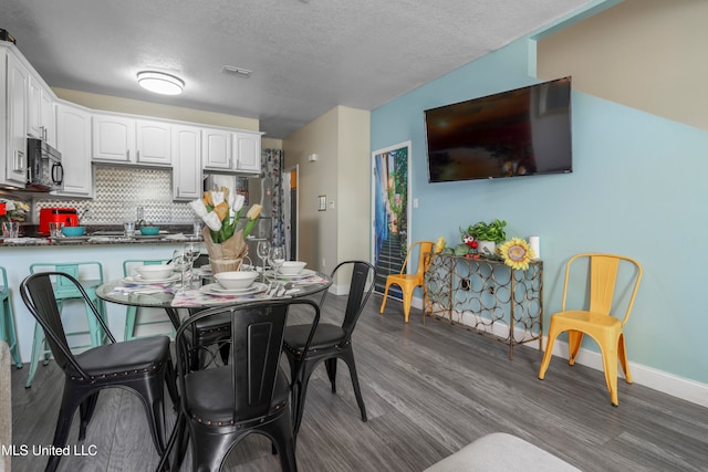 dining area featuring dark wood-type flooring and a textured ceiling