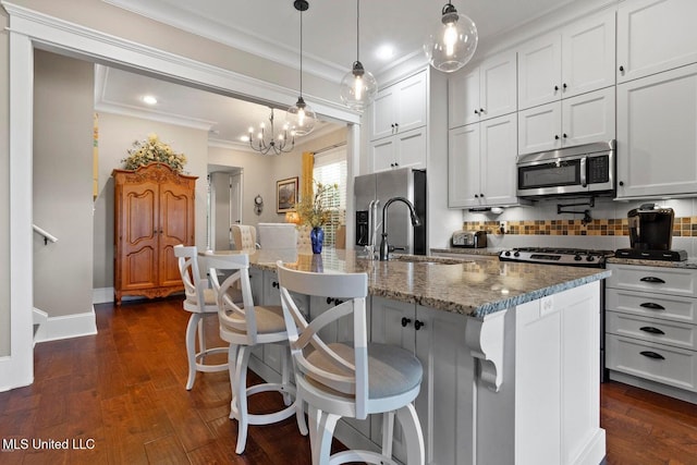 kitchen with white cabinetry, a center island with sink, decorative light fixtures, and appliances with stainless steel finishes