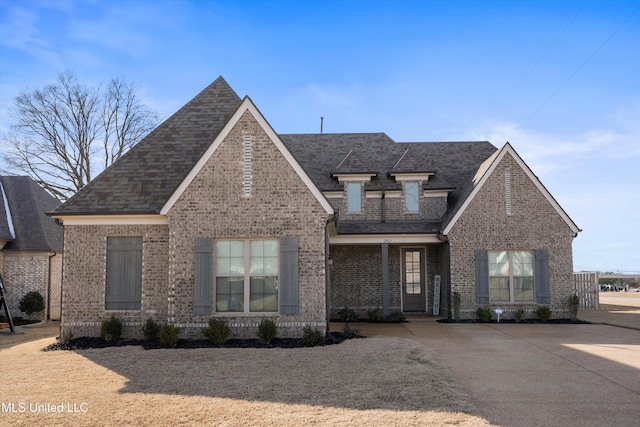 view of front of house featuring brick siding and roof with shingles