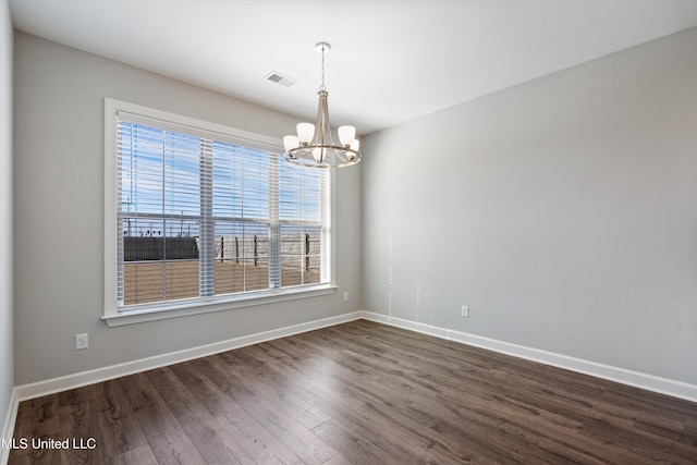 empty room with a healthy amount of sunlight, visible vents, dark wood-style flooring, and a notable chandelier